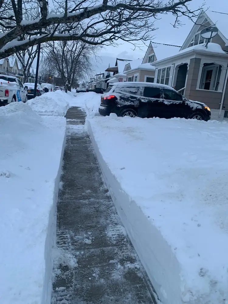 Sidewalk cleared between high snow banks after a Buffalo NY storm