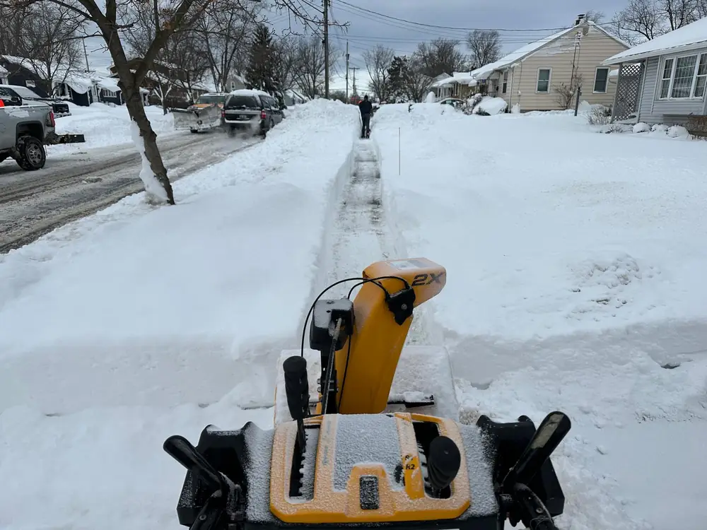 Snow blower cutting a path through deep snow on a Buffalo NY sidewalk